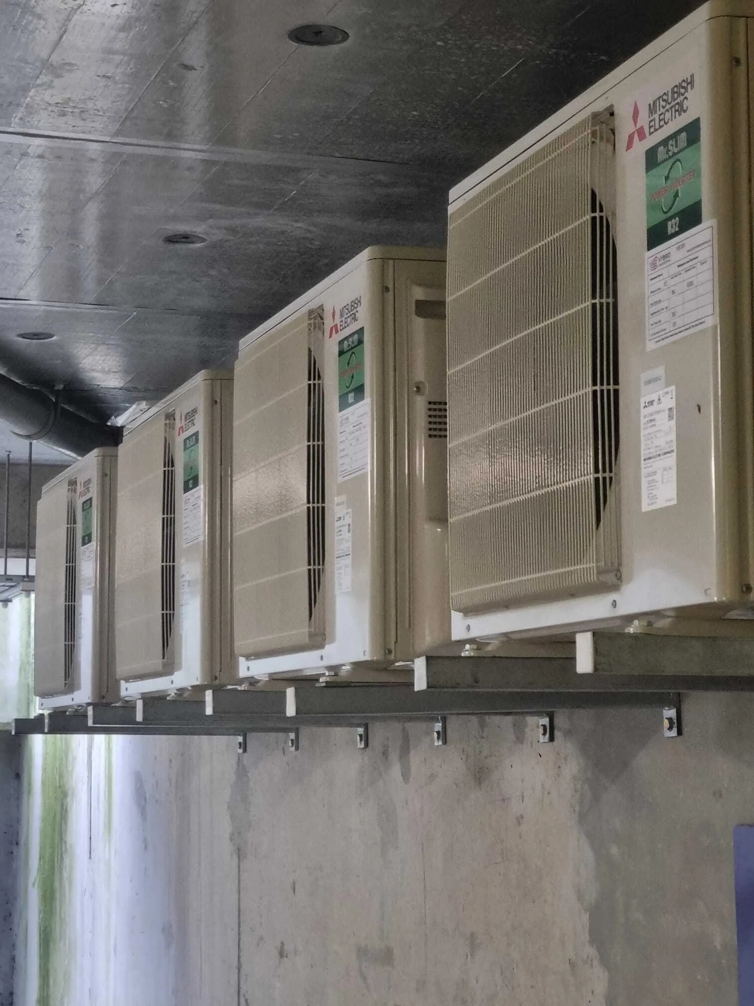 Row of Mitsubishi outdoor units on wall brackets